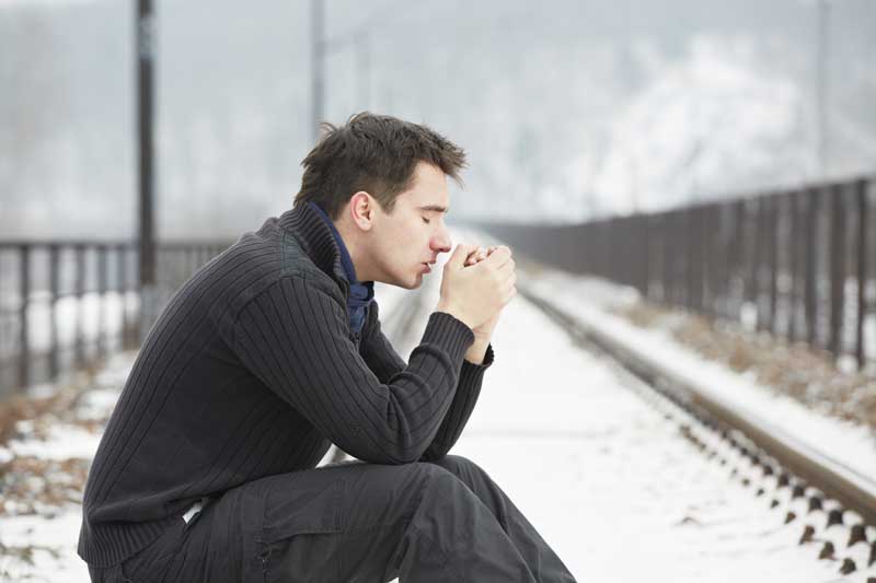 sad man sitting on a curb in the cold filled with grief